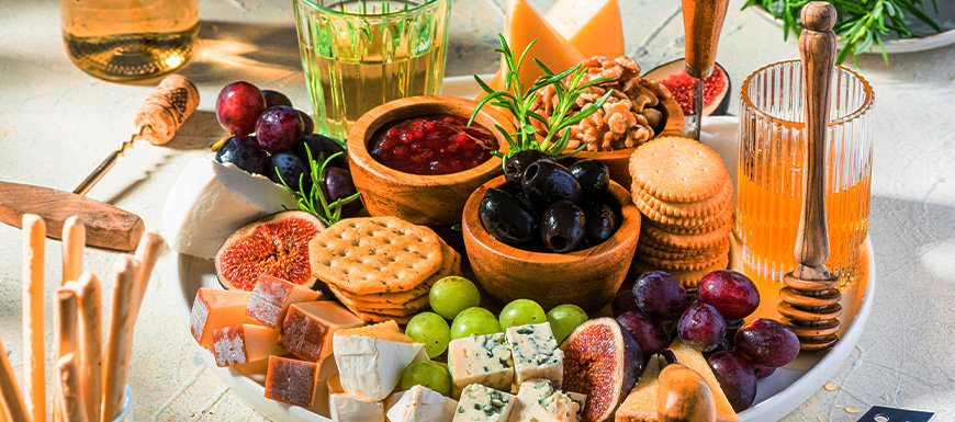 Charcuterie board with olives, jams, nuts, crackers, fruit, cheese.